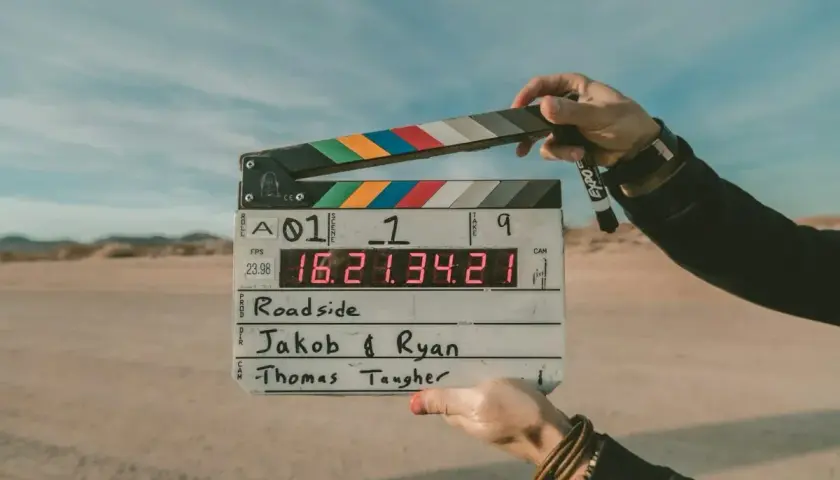 Pustynia, plan filmowy "Roadside". Dwie ręce trzymają klaps z napisem "Jakob & Ryan" i "Thomas Taugher". Opis miejsca.