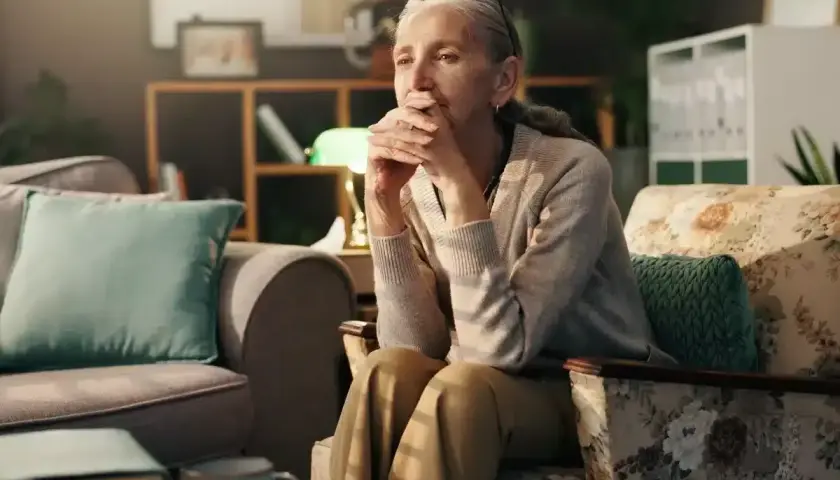Une femme âgée, le regard perdu, semble réfléchir aux changements de la ménopause et à la dépression qui peut l'accompagner.