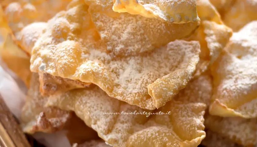 Chiacchiere croccanti, una deliziosa chiacchiere ricetta della nonna, cosparse di zucchero a velo.