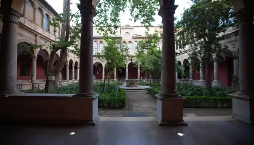 Patio interior con arcos y columnas en el barrio del Carmen, Valencia. Jardín frondoso con fuente central y árboles.