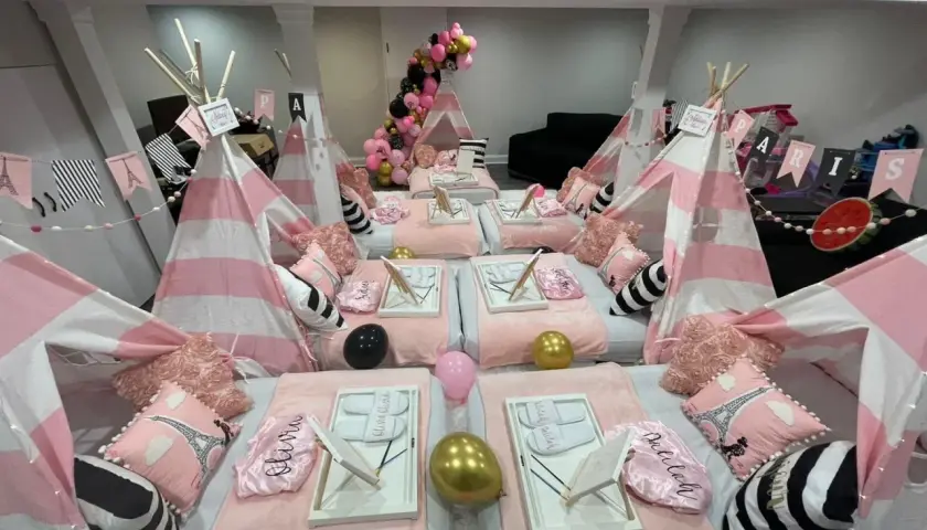 Urocze namioty tipi w różowo-białe paski, poduszki z Wieżą Eiffla i balony tworzą magiczne **pomysły na nocowanie** dla dziewczynek.