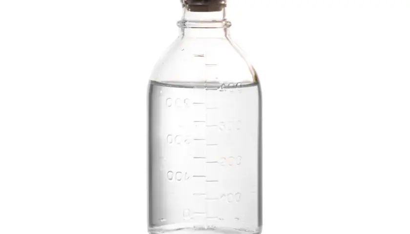 Szklana butelka z miarką, zawierająca klarowny płyn, przypominający denaturat.