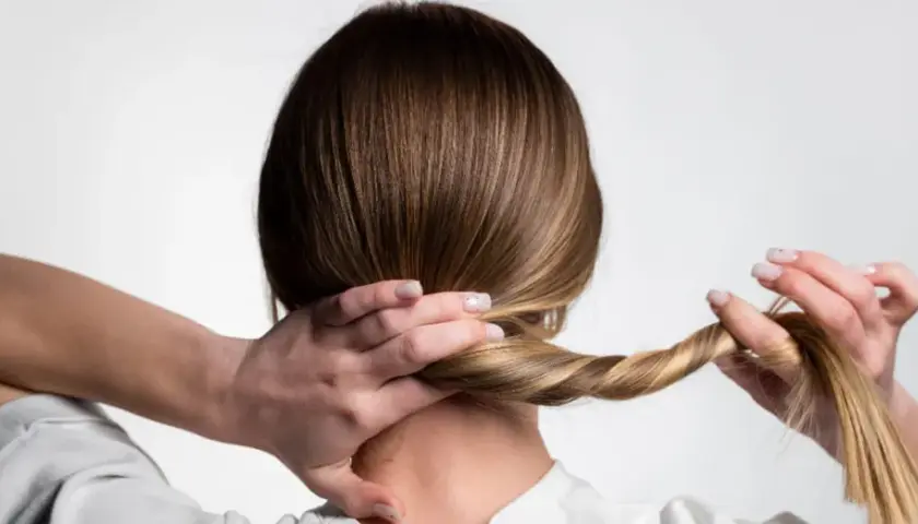 Manos trenzando el cabello para crear peinados para dormir, evitando enredos y luciendo un estilo cuidado al despertar.