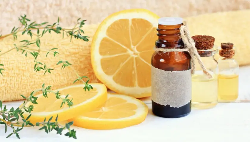 Aceite esencial de limón, con rodajas de limón y ramitas de tomillo. El limoneno es un componente clave.