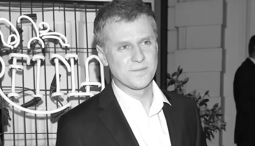 Krzysztof Reszpondek, znany z walki z chorobą, na tle neonowego napisu.