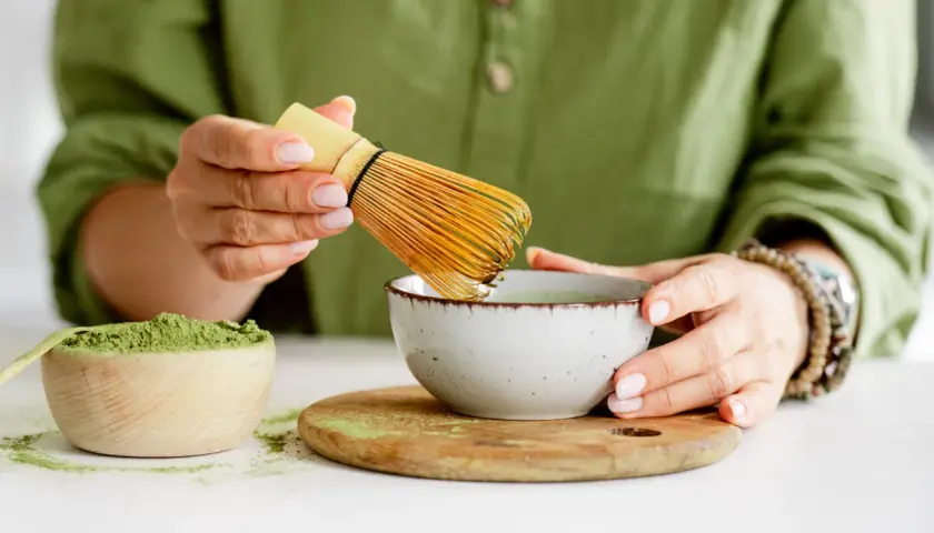 Przygotowanie najlepszej zielonej herbaty matcha. W drewnianej miseczce proszek, w ceramicznej miseczce napar, ubijany bambusowym miotełką.