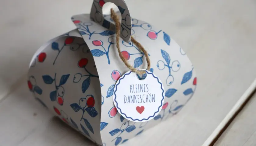Eine liebevoll gestaltete DIY Geschenkbox mit Beerenmuster und dem Anhänger "Kleines Dankeschön".