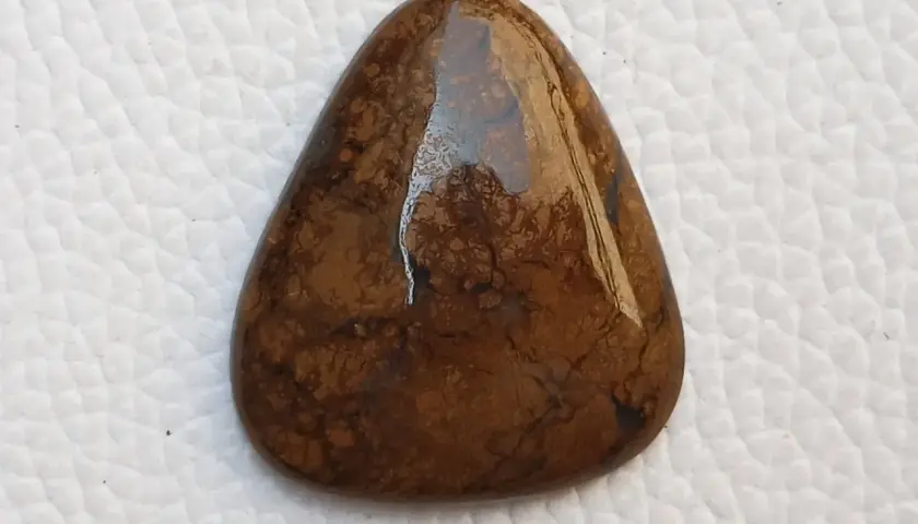 Piedra marrón con vetas oscuras, su significado evoca conexión con la tierra y estabilidad.