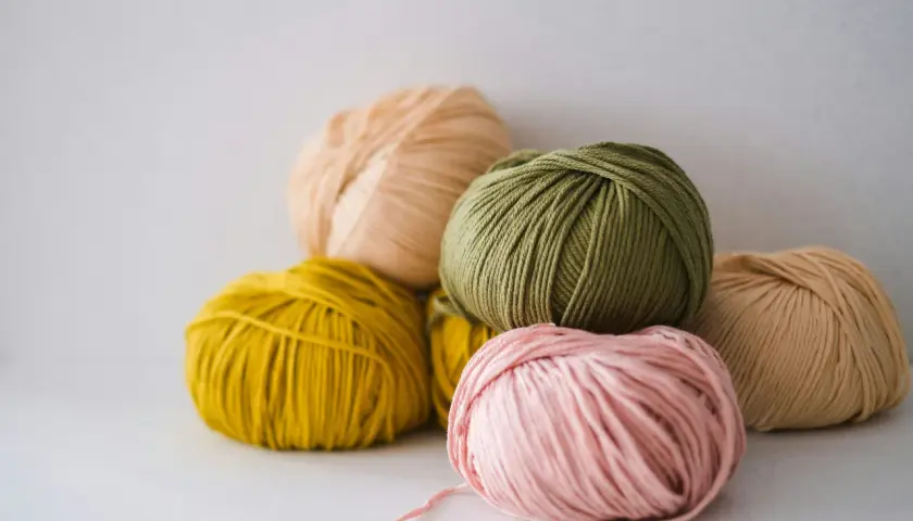 Pelotes de laine aux couleurs pastel, dont une rose pâle, une verte et une jaune. La matière semble être du nylon, parfaite pour des créations durables.