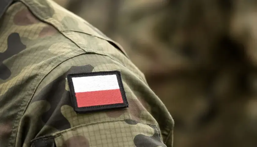 Na mundurze widoczna naszywka z flagą Polski. To symbol dumy i tradycji, nawiązujący do historii, w tym do stopni wojskowych II RP.