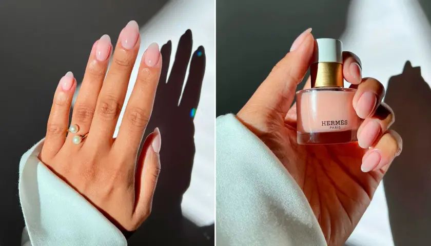 Manicura elegante con uñas nude, anillo de perlas y esmalte de uñas de Hermès.