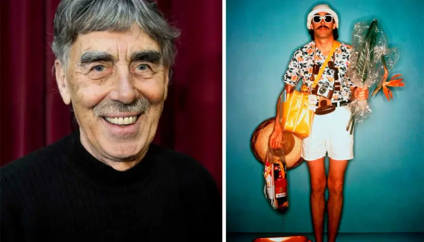 En äldre man med grått hår och mustasch, liknande en stig helmer frisyr, ler. Bredvid honom en turist med solglasögon och blommor.