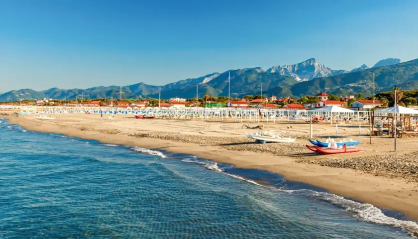 Plage de sable fin, mer bleue et montagnes en arrière-plan. Idéal pour savoir où aller en Toscane bord de mer.