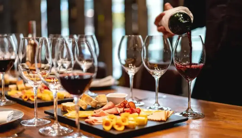 Une dégustation de vin à Paris, avec des verres remplis de vin rouge et des plateaux de fromages et charcuteries.