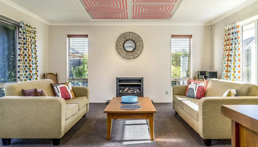 Salón acogedor con sofás, chimenea y un innovador techo radiante que calienta el ambiente.