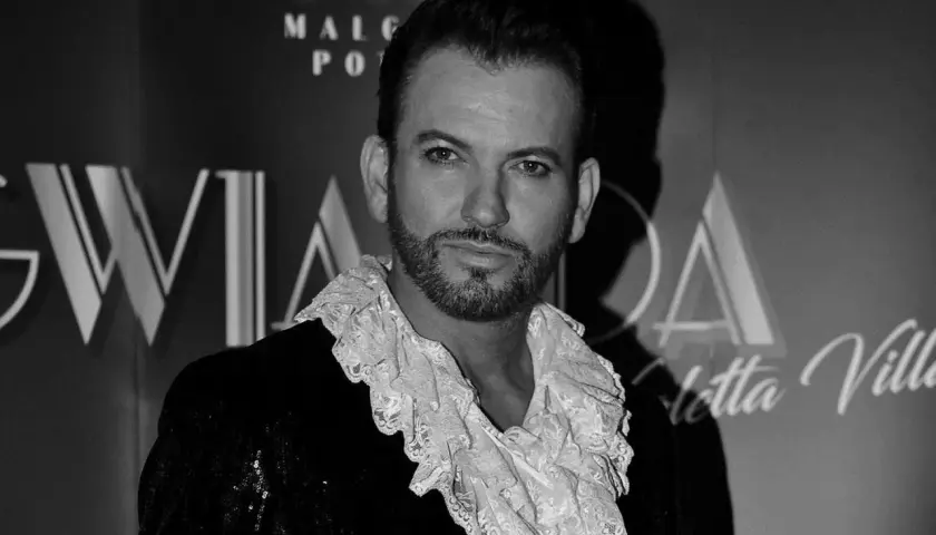 Gabriel Seweryn, syn, w błyszczącej marynarce i koronkowej koszuli z żabotem, pozuje na tle napisu "Gwiazda".