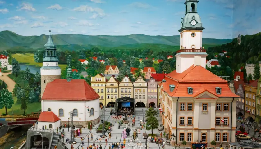Miniaturowy rynek w Jeleniej Górze, z wieżą ratuszową, kamieniczkami i tłumem ludzi.