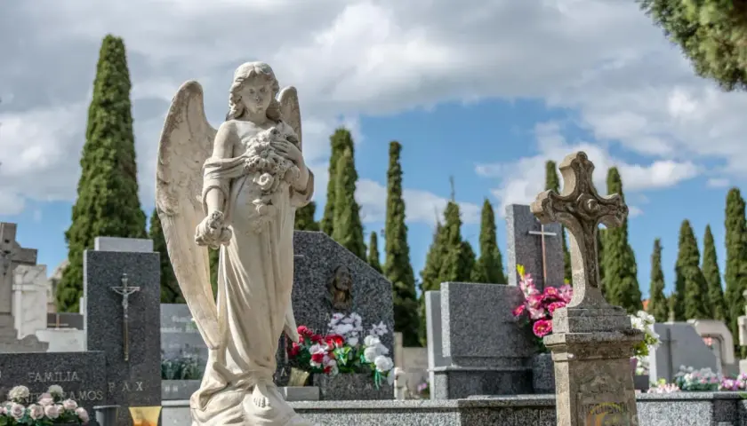 Anioł stróż na cmentarzu, symbol spokoju i pamięci. W tle wysokie cyprysy i nagrobki, tworzące melancholijną atmosferę.