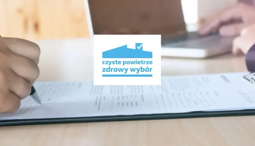 Dłoń pisząca na formularzu, logo "czyste powietrze zdrowy wybór".