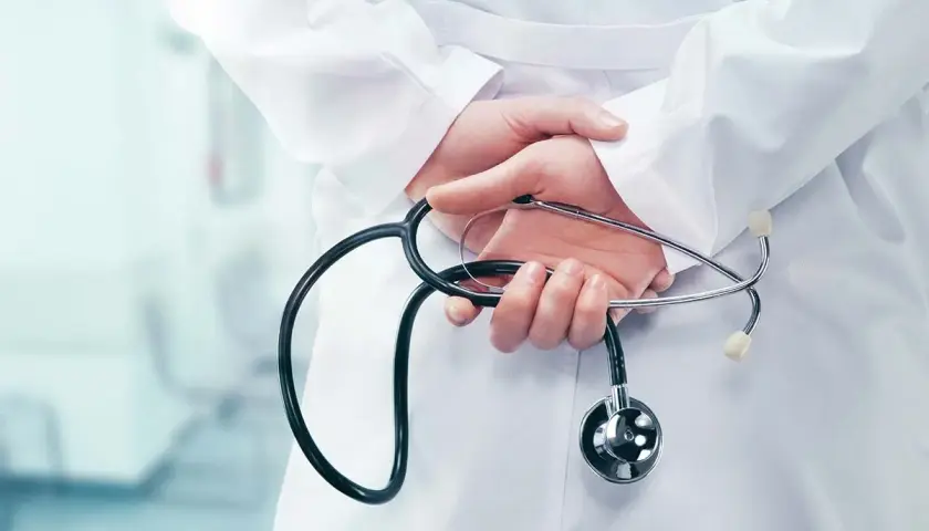 Mani di un medico con stetoscopio dietro la schiena, forse riflettendo su dimissioni dirigente medico e ferie non godute.