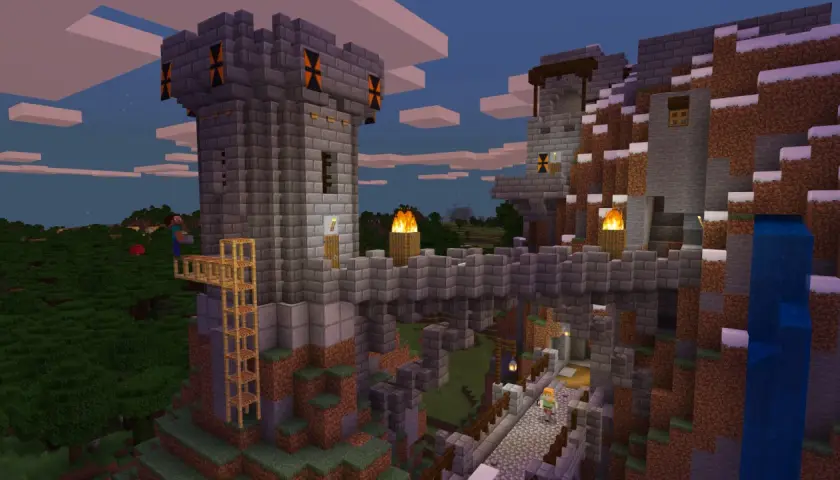 Kamienna twierdza w Minecraft, zbudowana na zboczu góry. Widać wieże, mosty, pochodnie i wodospad. Gra wymaga kreatywności!