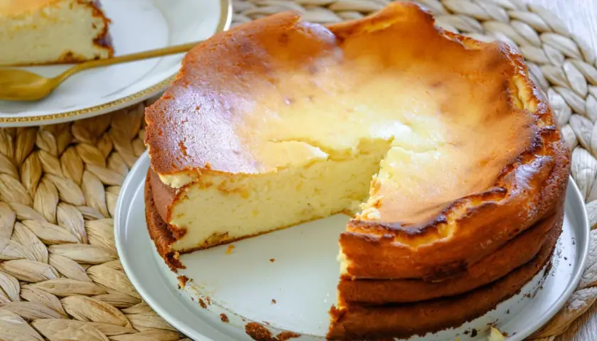 Pyszny, lekko zarumieniony sernik na wielkanoc, z kawałkiem już wyjętym, gotowy do podania.