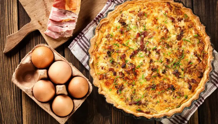 Comment faire une quiche : ingrédients pour une quiche savoureuse : œufs, lardons, et une belle quiche dorée prête à être dégustée.