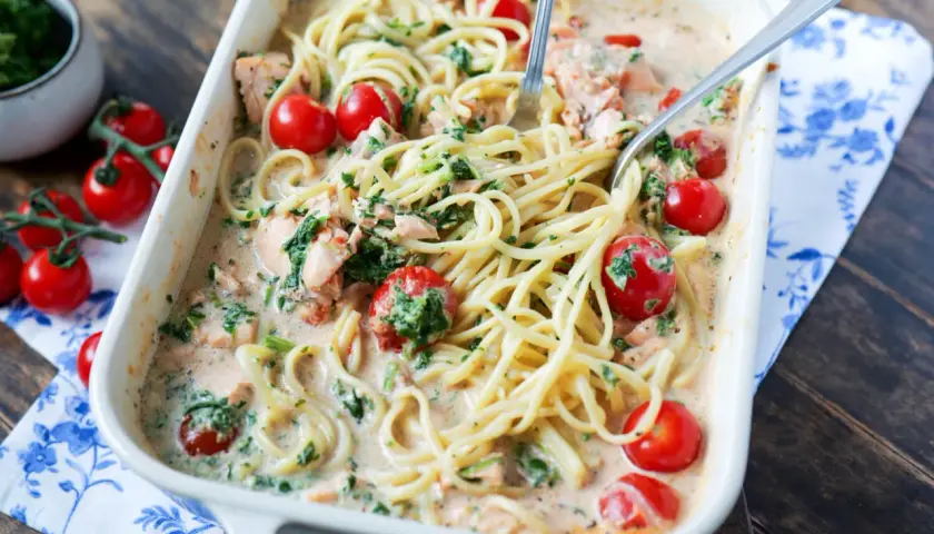 Cremige Lachs Spinat Pasta mit Kirschtomaten in einer Auflaufform, bereit zum Servieren.