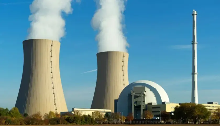 Dwie chłodnie kominowe elektrowni jądrowej z białym dymem na tle błękitnego nieba.