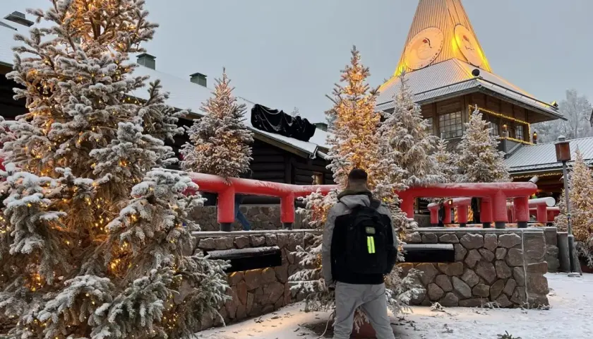 Ośnieżone choinki i budynek z wieżą tworzą magiczną atmosferę w Wiosce Świętego Mikołaja w Laponii.