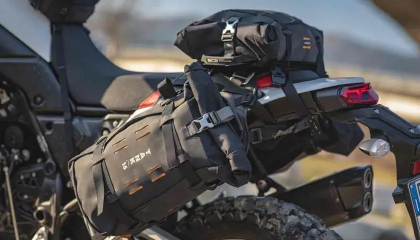 Borsa roll bag nera fissata sul retro di una moto da enduro, pronta per un'avventura.