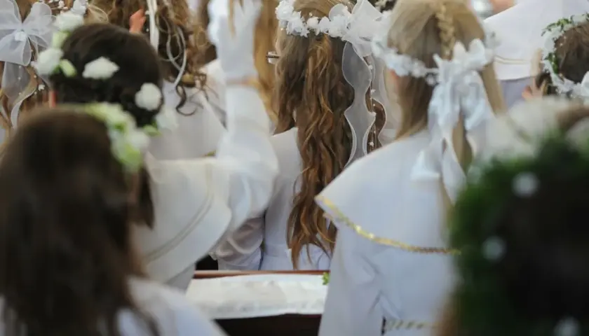 Dzieci w bieli, wianki na głowach, przygotowują się do komunii. Zastanawiasz się, ile daje chrzestny na komunię?