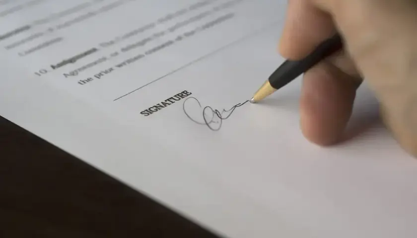Dłoń z długopisem składa podpis na dokumencie. To ważny moment, gdy podpisuje się umowę.