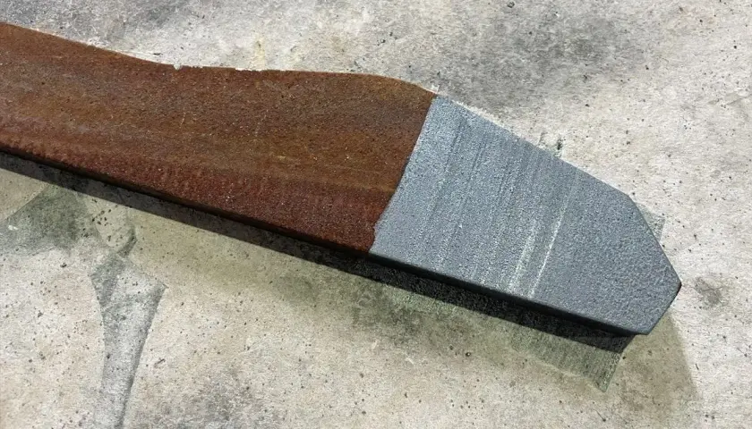Fragment metalu po jednej stronie zardzewiały, po drugiej idealnie czysty dzięki czyszczeniu laserowemu.