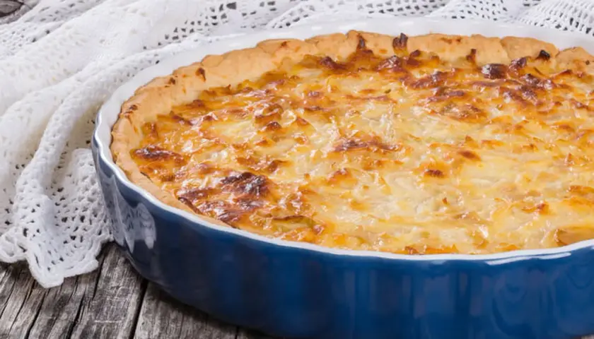 Quiche lorraine dorée dans un plat bleu. Le temps de cuisson et la température parfaits pour un délice croustillant.