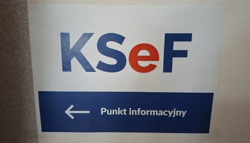 Tabliczka z napisem KSeF i strzałką w lewo do Punktu informacyjnego. Kto wymyślił KSeF? Zapytaj tutaj.
