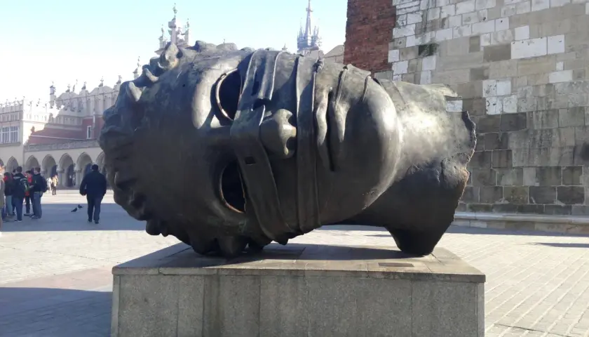 Gigantyczna, metalowa głowa, dzieło polskiego rzeźbiarza, leży na cokole na krakowskim Rynku.