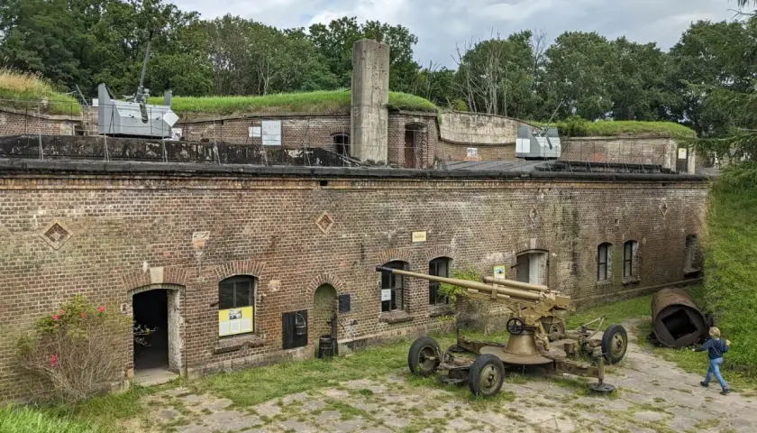 Fort Zachodni z działami na murach i ziemi. Dziecko biega obok zabytkowej broni.