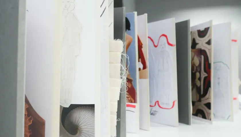 Un acheteur textile parcourt des croquis de mode, des échantillons de tissu et des motifs, imaginant de futures collections.