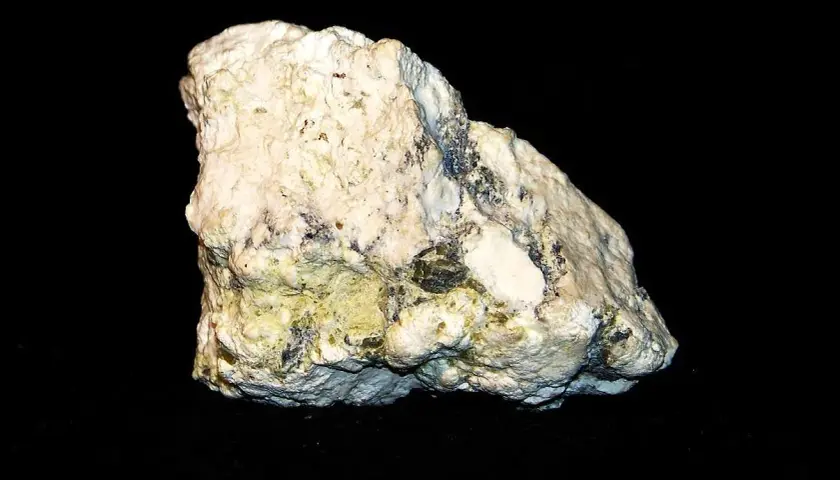 Biały, porowaty minerał z zielonkawo-żółtymi wtrąceniami, przypominający skałę, w której można znaleźć magnetyt.