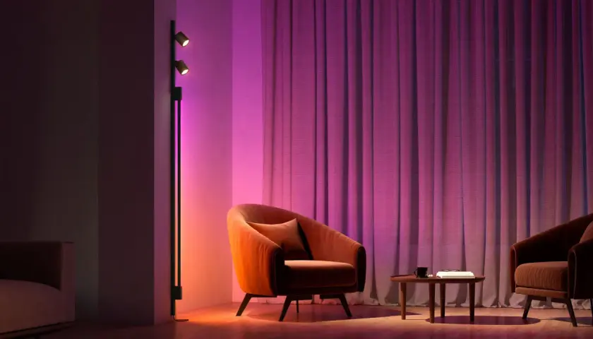 Sofá naranja y cortinas moradas iluminados por luces domoticas, creando un ambiente acogedor.