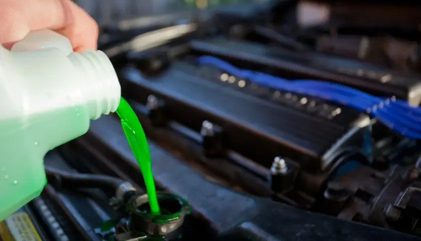 Vertiendo líquido refrigerante verde brillante en el radiador de un coche. El nivel líquido refrigerante es crucial para el motor.