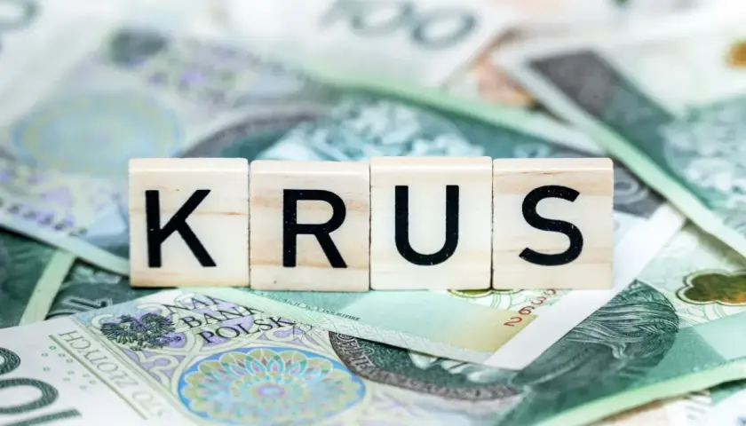 Litery KRUS na tle polskich banknotów. Zastanawiasz się, ile wynosi emerytura z KRUS?