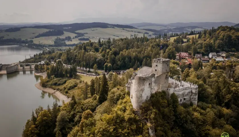 Zamek w Niedzicy góruje nad jeziorem i lasami. W oddali widać góry.