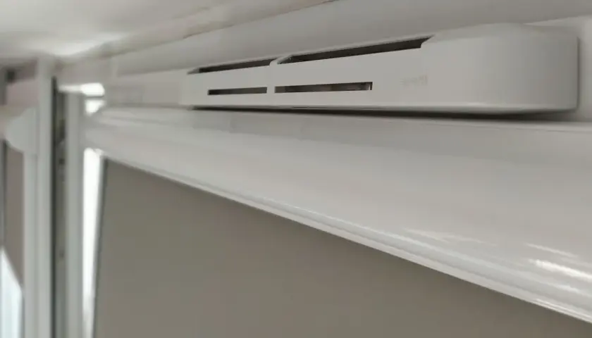 Białe okno z nawiewnikiem, zapewniającym świeże powietrze.