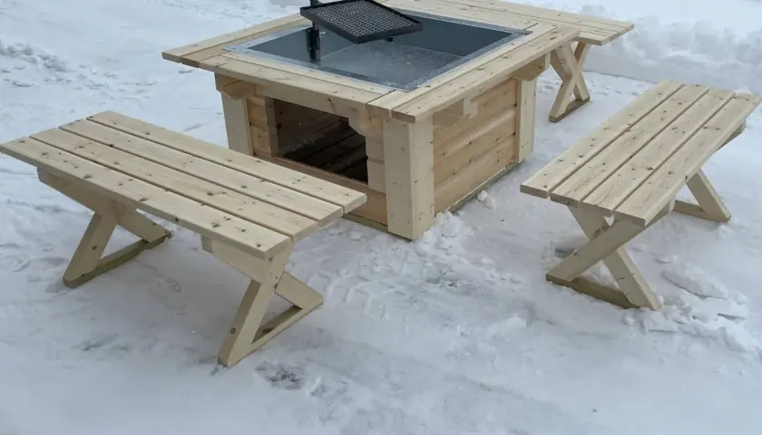 En ny grillplats i trä med bänkar, perfekt för grillplats inspiration i vinterlandskapet.