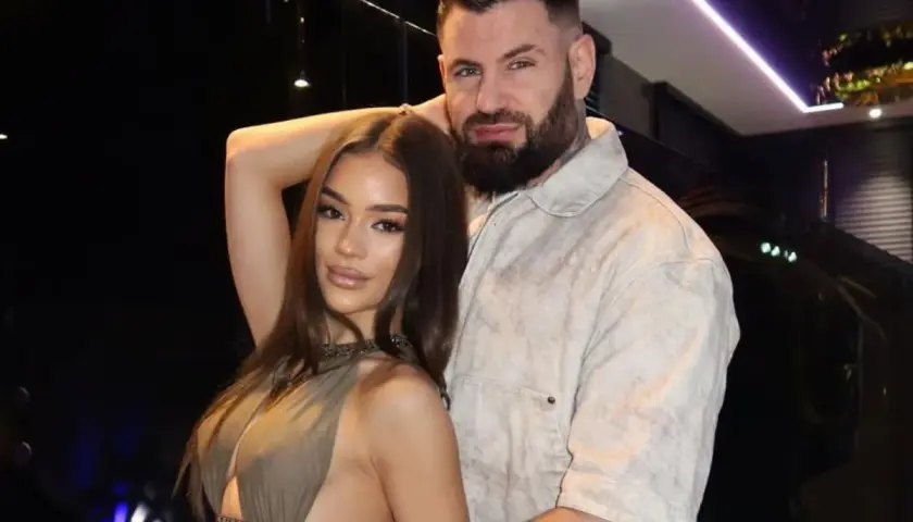 Wojtek Gola z dziewczyną, w eleganckich strojach, pozują do zdjęcia w stylowym wnętrzu.