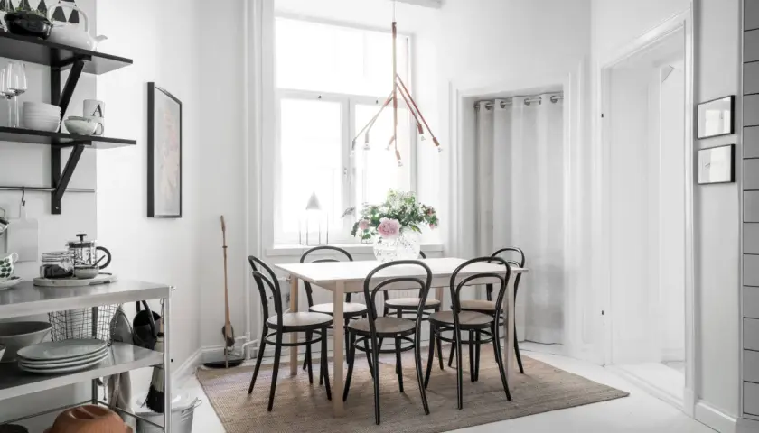 Ljust och luftigt kök med matbord och stolar, perfekt för matbord inredning inspiration. En stor vas med blommor pryder bordet.