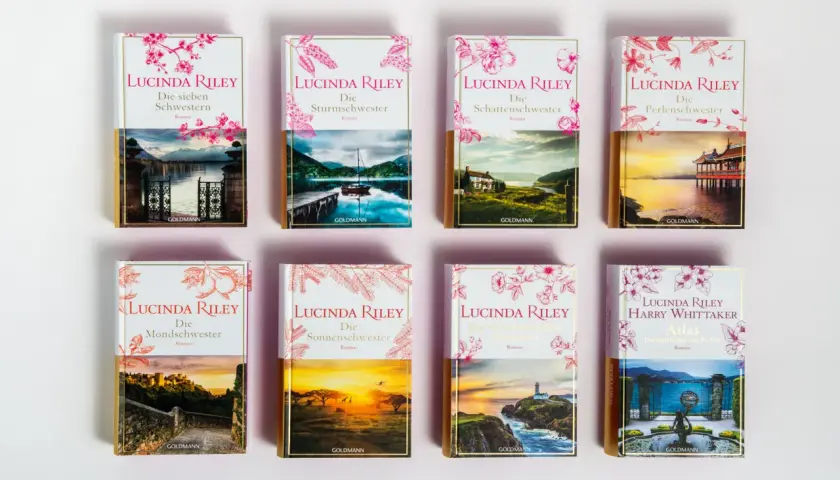 A collection of Lucinda Riley's "Die sieben Schwestern" book series, each with unique cover art depicting scenic landscapes.