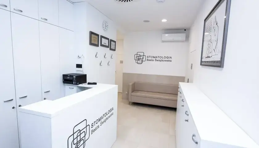 Recepcja nowoczesnej kliniki stomatologicznej z kanapą i logo.
